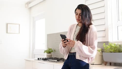 Woman Using Smartphone in Modern Bright Kitchen