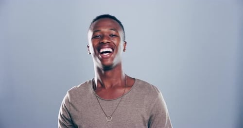 4k video footage of a young man laughing against a grey studio background
