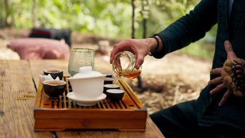 close-up The hands of a professional tea master who pours fresh natural green tea from a teapot