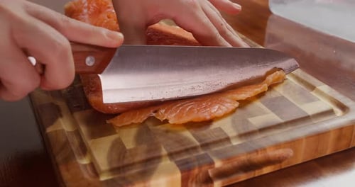 Raw salmon being sliced on a cutting board