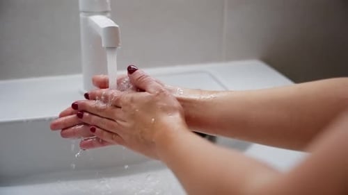 Closeup of a Woman Meticulously Rubbing Her Hands Together Under a Stream of Water Ensuring Each