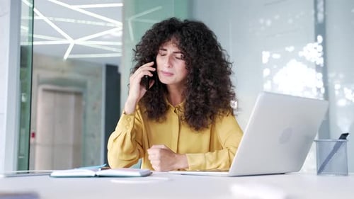 Frustrated Woman Talking on Smartphone in Office