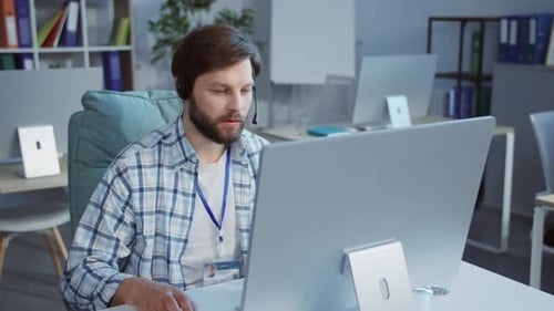 A Man at His Desk Headphones on Focused on His Computer Work