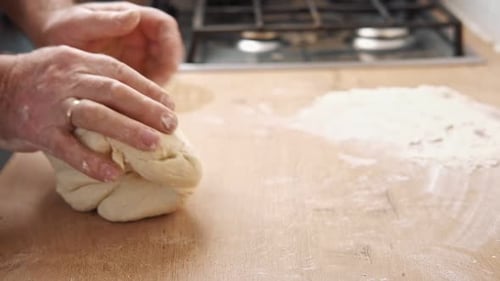 Hands Kneading Dough on Wooden Kitchen Surface