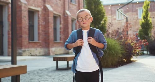 Portrait of a funny school boy with backpack looking at the camera and smiling