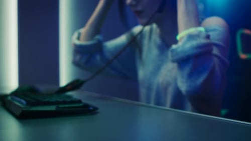 Woman gamer playing video game, headphones on desk