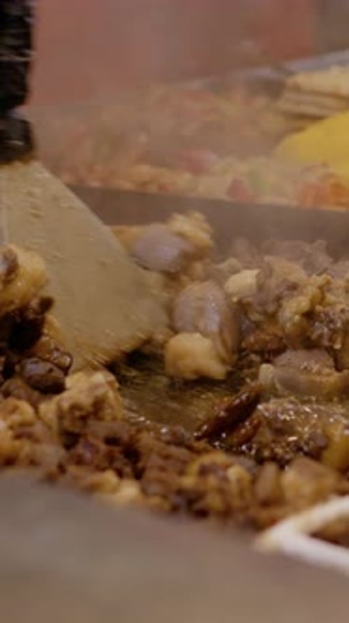 Vertical video Street food vendor cooking meat on hot plate