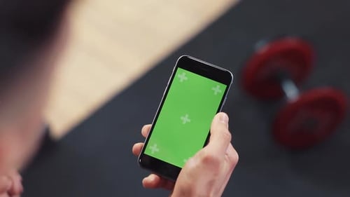 Close Up Hand Man Use Phone with Vertical Green Screen in Sport Club Gym Dumbbell Headphone Touch