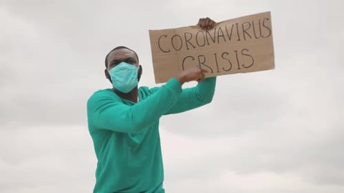 Man Holding "Coronavirus Crisis" Sign Wearing a Mask