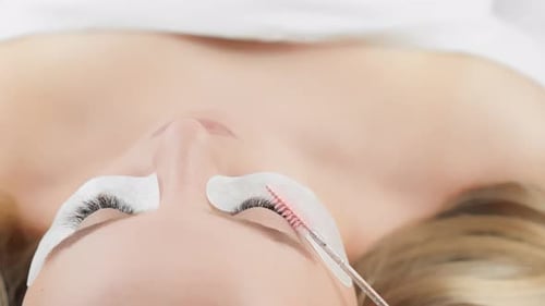 Una mujer joven sobre el procedimiento de extensiones de pestañas en una cosmetóloga de pestañas Hermosa chica en
