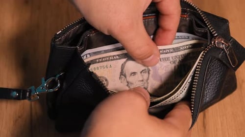 Close-up of the hands of a person sorting out money in a leather black wallet, man hand gives cash