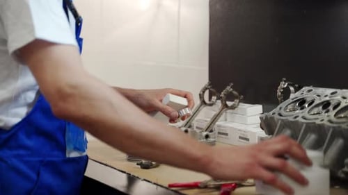 Professional Mechanic Assembles Engine Kit Arranging Pistons Rings Liners on Workbench for