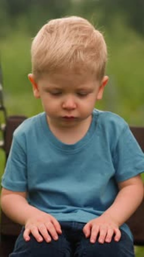Pensive Boy Sitting on Swing Outdoors