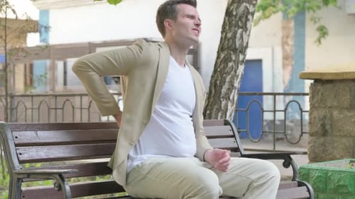 Young Man Rubbing Lower Back in Discomfort