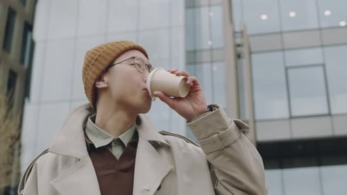 Asian Guy Drinking Takeaway Coffee on Street