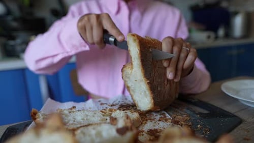 Hands Slice Bread in Kitchen with Knife