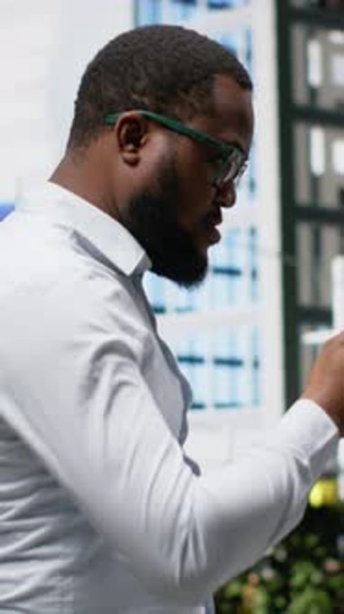 Vertical Video African American Adult with Casual Style Checking His Smartphone Apps