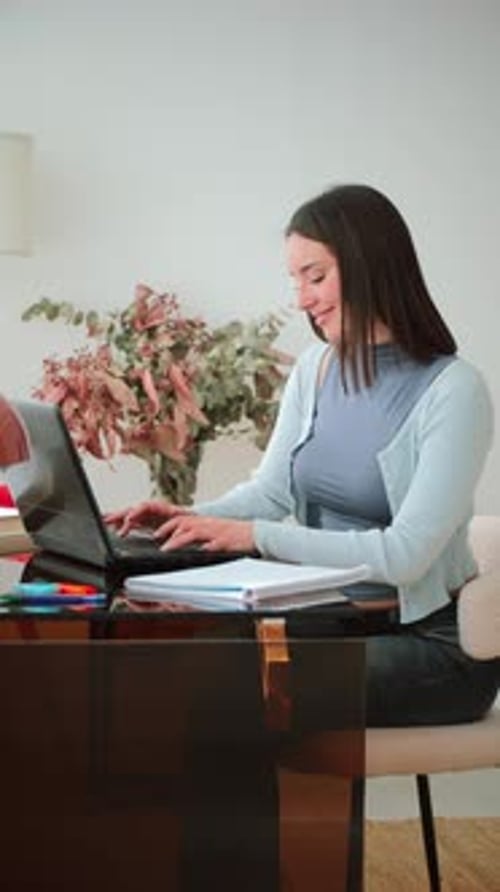 Woman Working at a Desk Using a Laptop