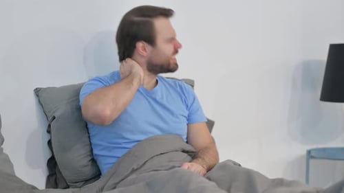 Man with Neck Pain Sitting in Bed