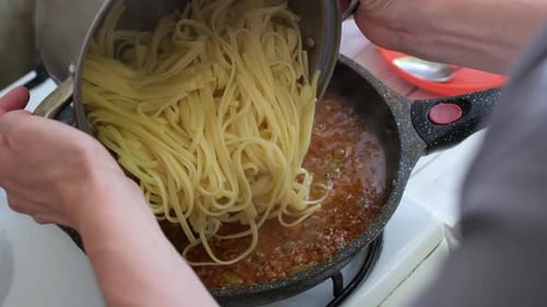 Overhead shot of a person adding noodles to sauce
