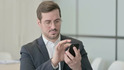 Man With Glasses Using Phone in Office