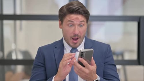 Excited Adult Man Celebrates Success with Cell Phone