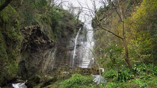 Mountain waterfall, water flows from the top of the rock and falls down breaking into splashes