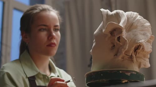 Young Woman Forming Clay for Bust in Workshop