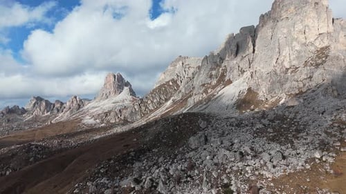 Rugged mountain peaks under a partly cloudy sky with rocky slopes and patches of sunlight