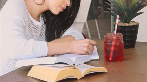 Young student focused on homework and university studies in a local city cafe