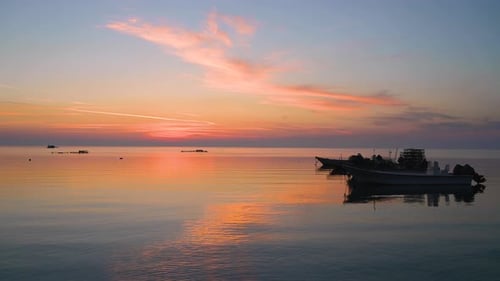Fisherman boats floating on calm water waves over colorful beautiful twilight sunrise clouds sky bac