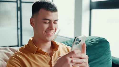 Man Smiling at Mobile Phone Indoors