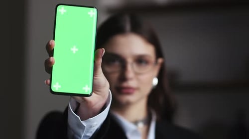 Female Presenter Displaying Digital Content on Chroma Key Greenscreen Using Smartphone in Urban