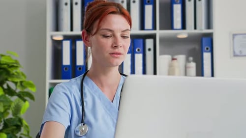 Therapist Female Hospital Worker Working at a Computer While Sitting in a Medical Office