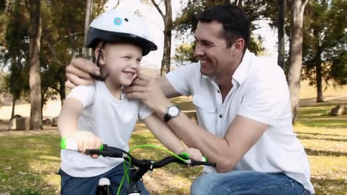 Father teaches son bicycle safety on a sunny park pathway adventure