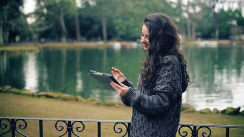 Relaxed pretty brunette using digital tablet at the park