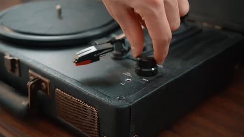 A hand turns on a turn table and turns up and down the volume.