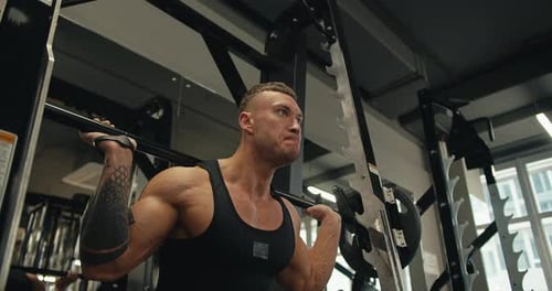 Man Squats With Barbell Weight at Gym