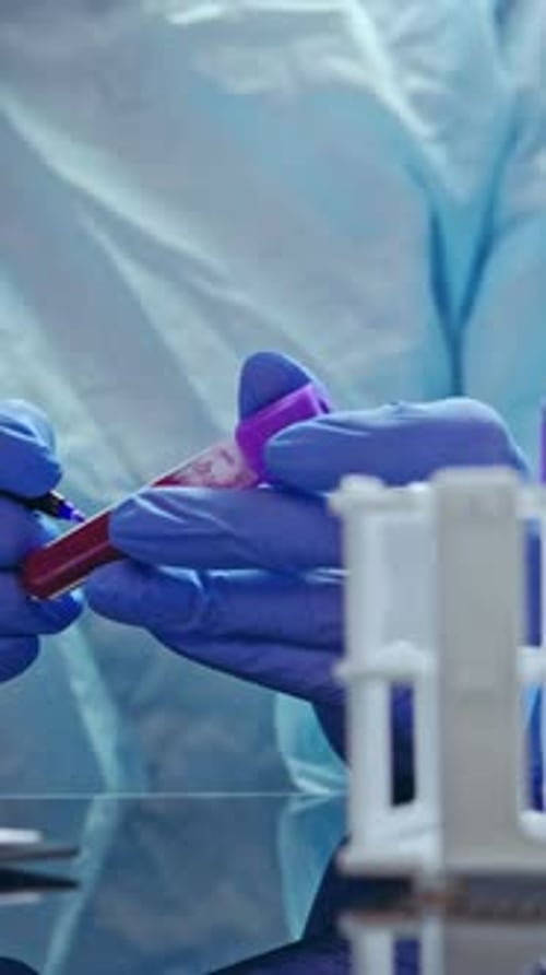 Gloved Hands Handling Vial of Blood in Lab