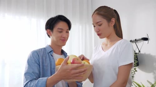 Smiling Couple with Fresh Fruit in Kitchen