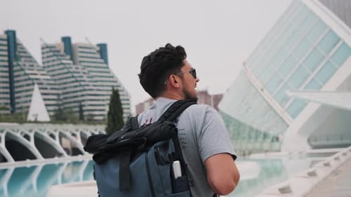 Young Man Carrying a Backpack and Walking on the City Rear View of a Man Strolling Alone in the City