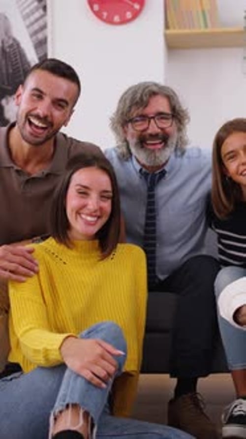 Portrait of Happy Caucasian Family Posing Smiling Looking at Camera Hugging Around Table Indoors