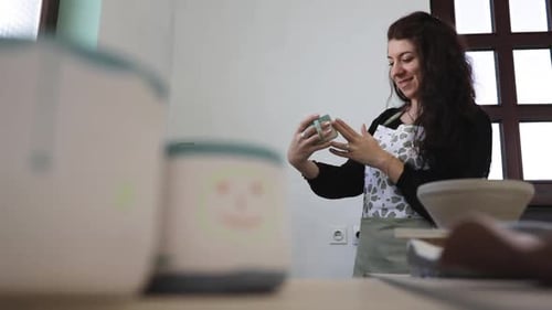Young woman in pottery studio, checking her handmade ceramics after making it.