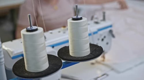 Close Up of White Sewing Threads are Unwound From Spools on a Sewing Machine Media Production Sewing