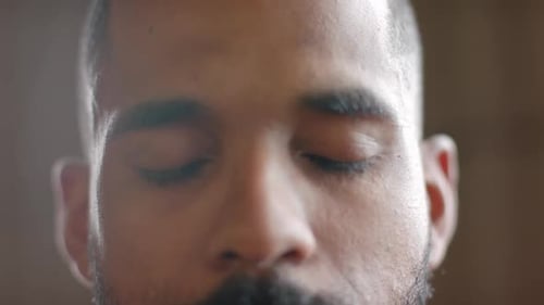 Portrait close up of focused biracial man opening eyes and looking to camera in slow motion