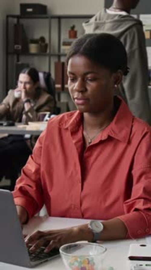Vertical of Black Female Programmer Working on Laptop in Diverse Office