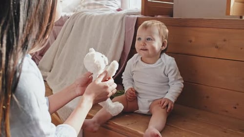 Mother Giving Plush Toy To Excited Baby Biting It