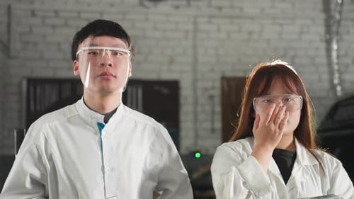 Technicians Adjust Safety Glasses While Holding Tablets in Automotive Workshop