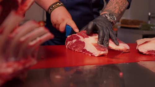 Butcher Cutting Raw Meat with Knife in Kitchen