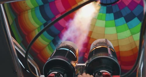 Slow motion close up view of the flame inside of a colorful hot air balloon being inflated before